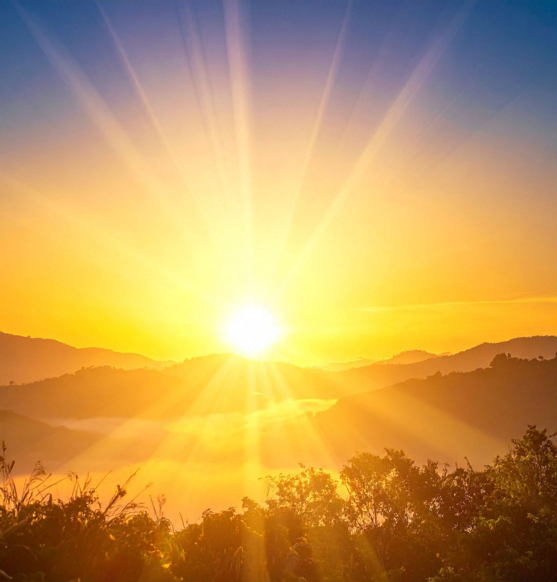 Sunrise over a mountain landscape, rays of light breaking through the clouds